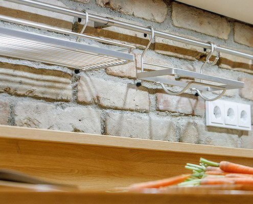 Baumann Küchen - Detailansicht von Edelstahl Wandhaltern und Ablagemöglichkeiten.