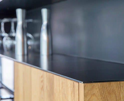 Baumann Küchen - Detailansicht eines schwarzen Regalfaches aus Metall. Innenliegend in einer Echtholz-Küchenfront.