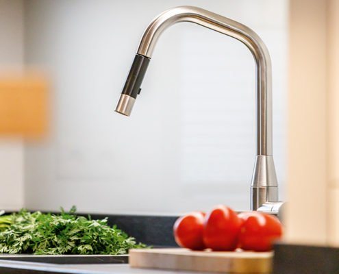 Baumann Küchen - Moderner Wasserhahn mit Brausefunktion in heller Küchenumgebung.