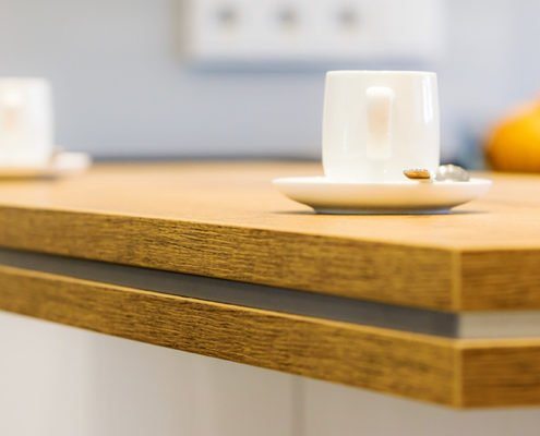 Baumann Küchen - Detailansicht einer Massivholz Arbeitsplatte mit einem integrierten Band aus Edelstahl