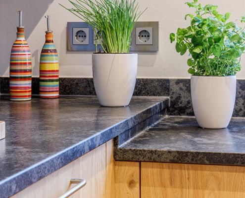 Baumann Küchen - Detailaufnahme zweier höhenversetzten Arbeitsplatten aus schwarzen Granit mit hellgrauen Einschlüssen.