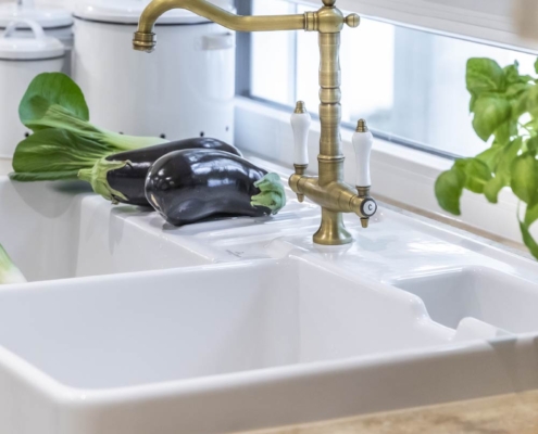 Baumann Küchen - Weißes Spülbecken aus Keramik mit einem edlen Wasserhahn aus Messing im Retro Design.