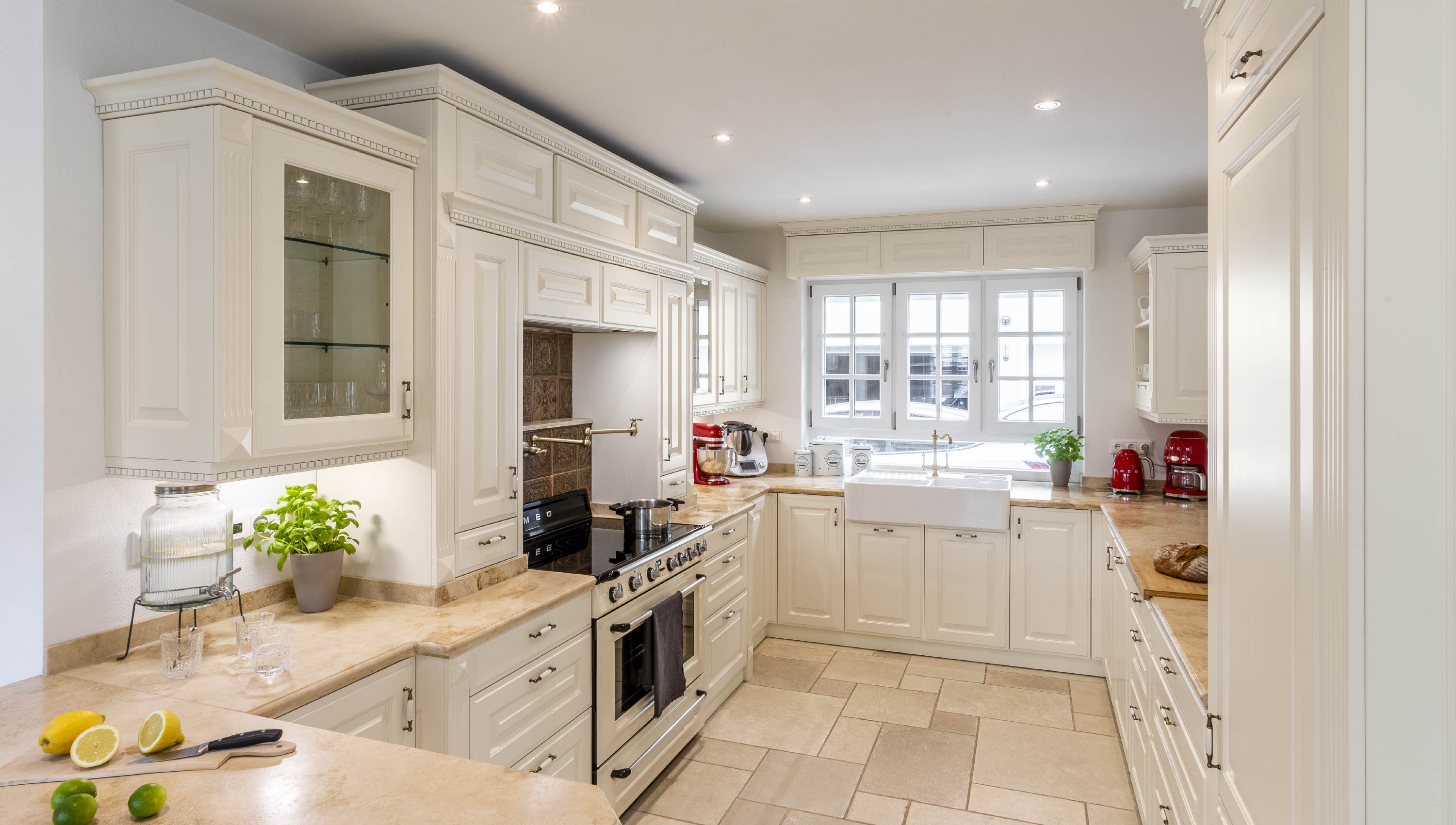 Baumann Küchen - Eine helle hochwertige Landhaus Küche mit weißen Fronten und einer Marmor Arbeitsplatte.